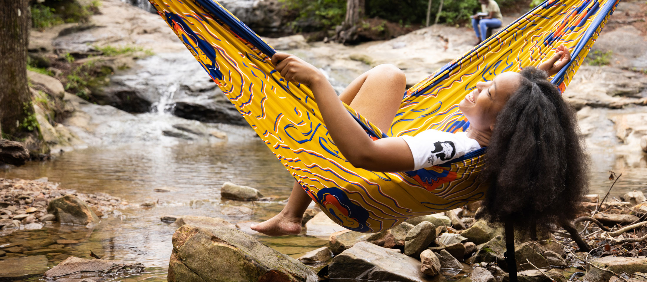 Girl sitting in a hammock over a stream. Visit outdoorafro.org